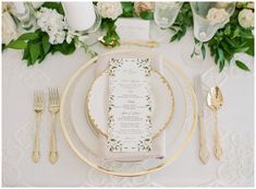 the table is set with white and gold place settings