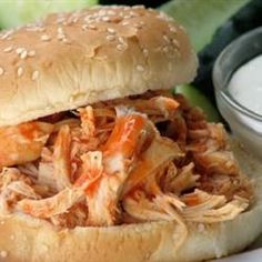 a pulled pork sandwich sitting on top of a white plate next to lettuce