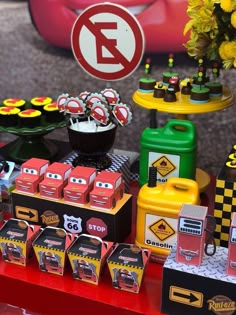 cars birthday party food and decorations on a red table with yellow flowers in vases