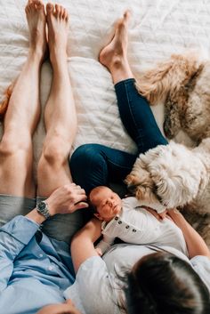 a woman laying on top of a bed next to a white dog and a man