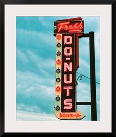 a neon sign that says donuts on the side of a building with clouds in the background