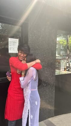 two women hugging each other in front of a building