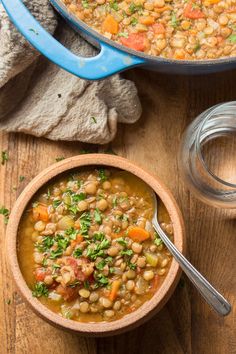 a bowl of beans and carrots with a spoon in it on a wooden table