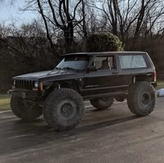 a black jeep parked in front of some trees