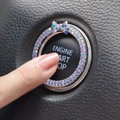 a woman's finger is pressing the start button on a car engine control knob