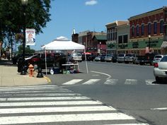 an intersection with cars parked on both sides and tents set up in the street to sell items