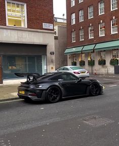 a black sports car is parked on the side of the road in front of some buildings