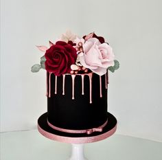 a black cake with pink and red flowers on top