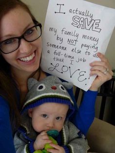 a woman holding a baby in her arms with a sign on it that says i actually save my family money by not paying a full time to do love