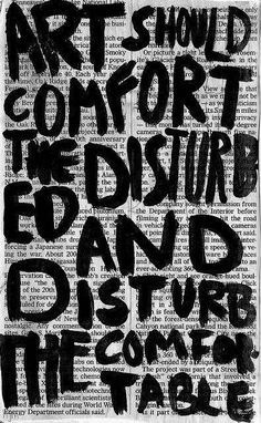 the words art should comfort the disturb and destroy the table written in black ink on an old newspaper