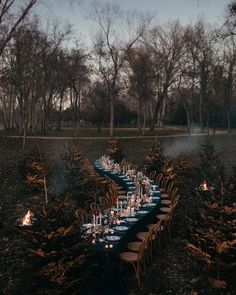 a long table is set up in the middle of a field with candles and place settings