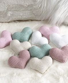 several crocheted hearts are arranged on a white furnishing area next to a furry pillow