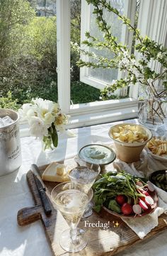 a wooden tray topped with lots of food next to a window