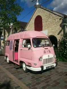 an old pink van is parked in front of a church on a cobblestone street