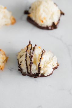 coconut cookies with chocolate drizzled on them sitting on a marble counter top