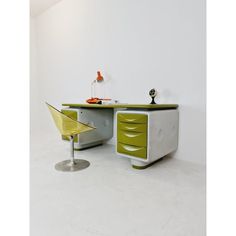 a green and white desk with a yellow chair next to it on a white floor