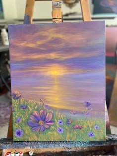 an easel with a painting on it that has flowers in front of the sun