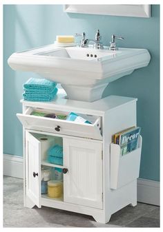 a white sink sitting under a mirror next to a bathroom cabinet with towels on it