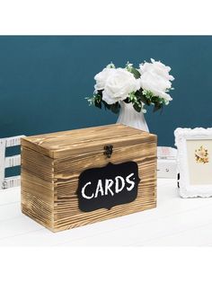 a wooden box sitting on top of a white table next to flowers and framed pictures