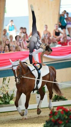 a woman riding on the back of a brown horse in front of a large crowd