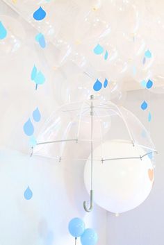 an umbrella is suspended from the ceiling with blue confetti balloons floating around it