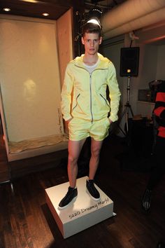 a mannequin dressed in yellow stands on a box