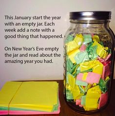 a jar filled with yellow and pink paper next to a notepad on a table