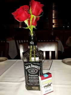 there is a bottle with roses in it and a card on the table next to it