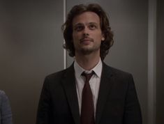 a man wearing a suit and tie standing next to another man in an elevator room