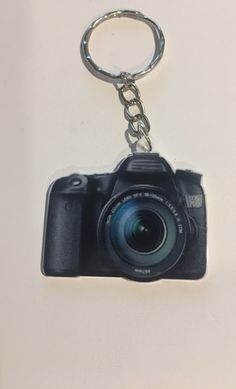 a camera keychain hanging from a white wall