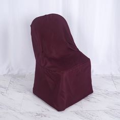 a maroon chair cover sitting on top of a white marble floor next to a wall