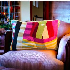 a colorful pillow sitting on top of a brown chair