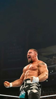 a man standing on top of a wrestling ring holding his fist up in the air