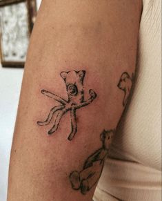 a woman's arm with an octopus and cat tattoo on the left side of her arm