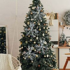 a decorated christmas tree in the corner of a room with white walls and wooden floors