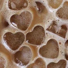 some brown and white heart shaped rocks in water with bubbles on the surface, close up