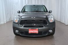 the front end of a gray mini cooper in a showroom with white drapes