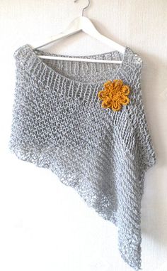 a knitted sweater with an orange flower on the front and back, hanging from a hanger