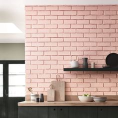 an image of a kitchen with pink brick walls and dark green cupboards on the counter