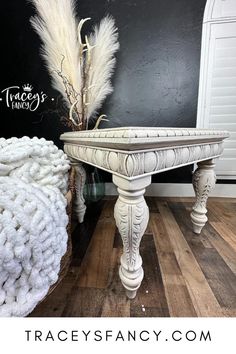 a white table sitting on top of a hard wood floor next to a black wall