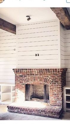 an old brick fireplace is being remodeled with white paint on the walls and wood beams