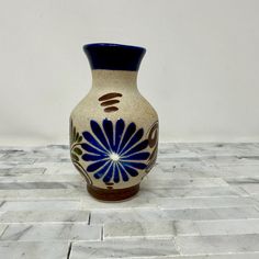 a blue and white vase sitting on top of a tile floor