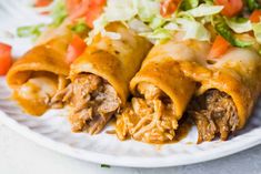 two burritos on a plate with lettuce and tomato salad in the background