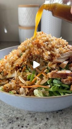 someone pouring dressing onto a salad in a bowl