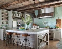 a kitchen with two stools in front of the island and an oven above it