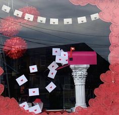 a pink mailbox sitting on top of a window next to a red and white flag