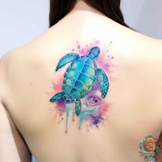 the back of a woman's shoulder with a watercolor turtle tattoo on it