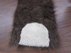 a close up of a furry animal's tail on a wooden table with white and brown fur