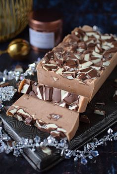 three pieces of chocolate fudge with white and brown toppings on a black plate