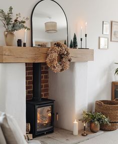 a living room with a fireplace, mirror and potted plants on the mantel